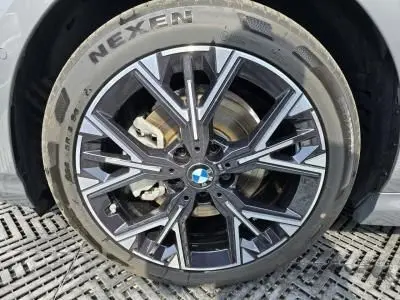 Gros plan sur la jante en alliage 18 pouces style 975 M bicolore d'une BMW Série 1 gris Skyscraper, avec logo central BMW visible.