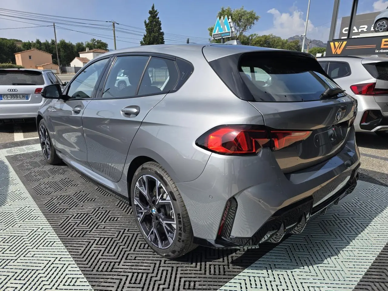 BMW Série 1 120d M Sport gris Skyscraper vue 3/4 arrière droit avec jantes 18 pouces et feux LED distinctifs.