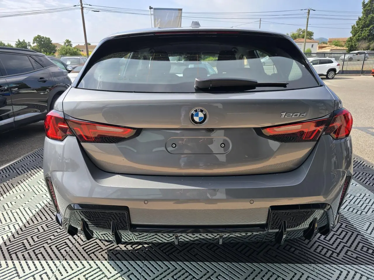 Vue arrière d'une BMW Série 1 120d gris Skyscraper avec feux LED et diffuseur noir M Sport visible.