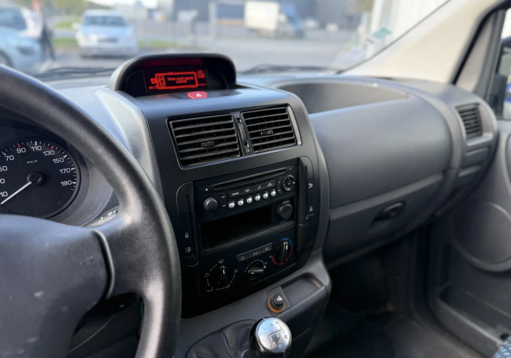 Vue intérieure côté conducteur du tableau de bord noir et levier de vitesses manuel du Fiat Scudo Fourgon blanc de 2015.