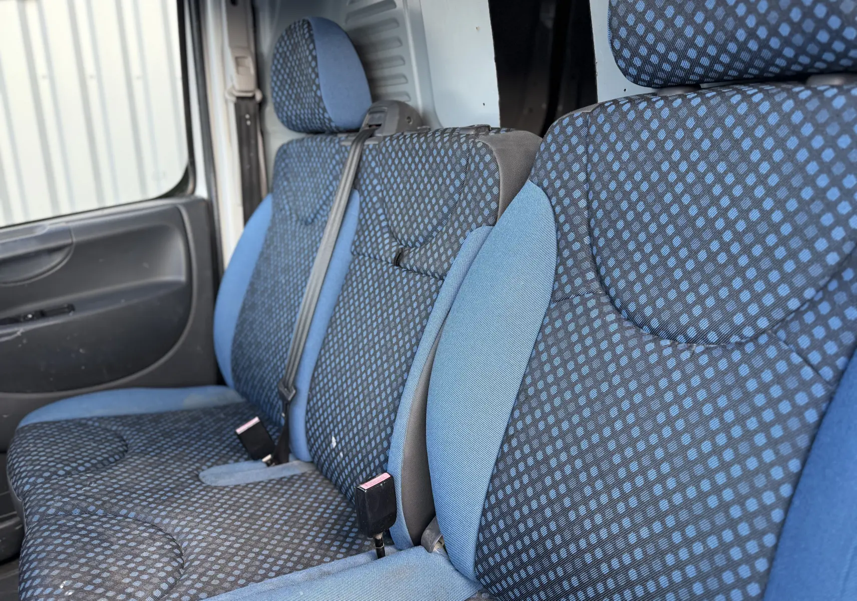 Vue intérieure rapprochée des sièges avant en tissu bleu à motifs du FIAT Scudo Fourgon blanc, version 2015.