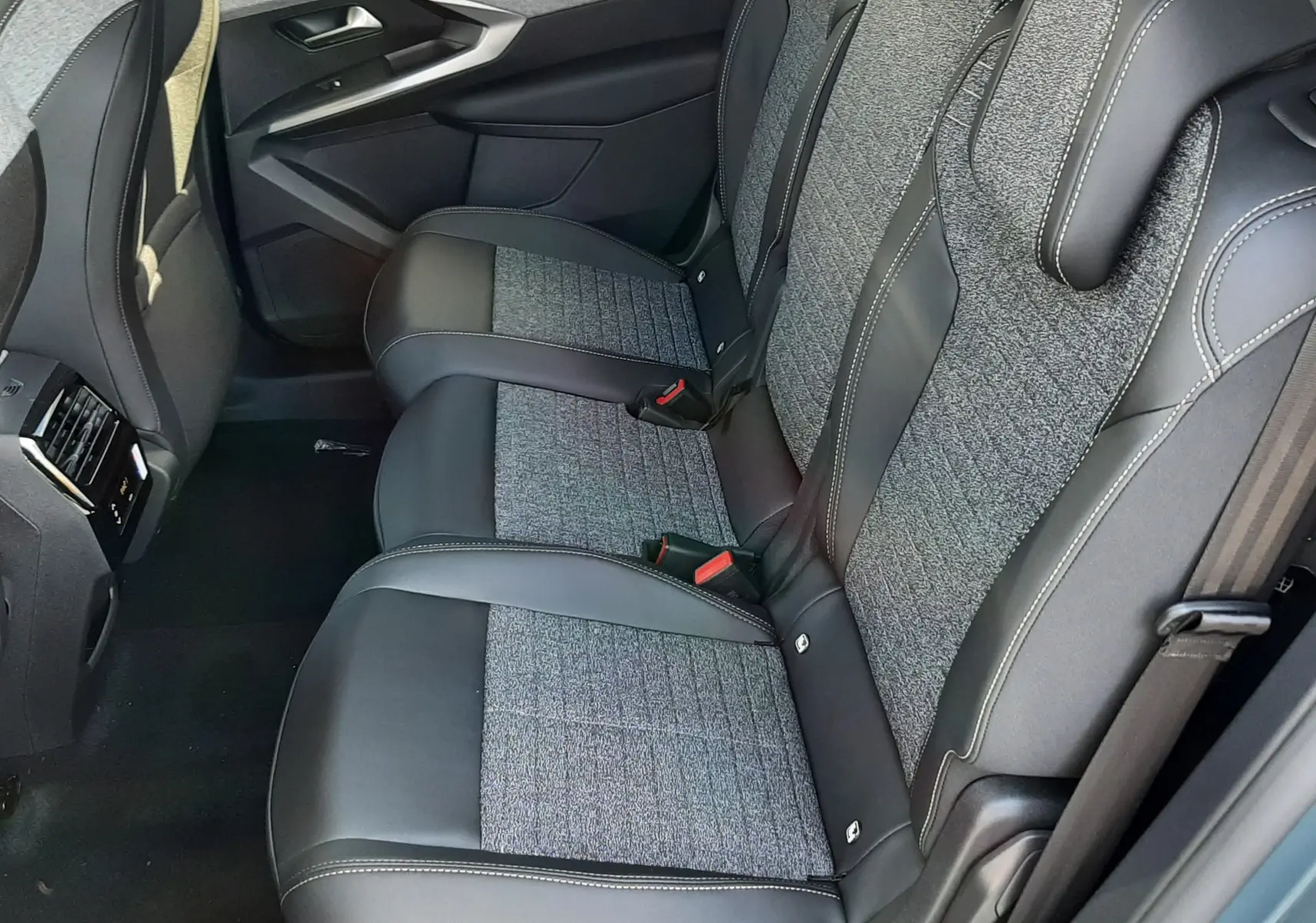 Vue intérieure côté droit des sièges arrière en tissu et cuir gris du Peugeot 5008 III Hybrid 2025 bleu Ingaro.