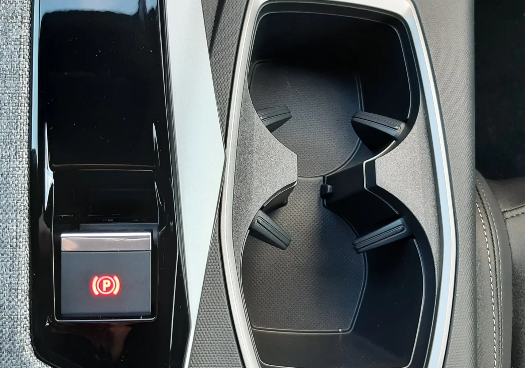 Gros plan sur la console centrale noire et grise avec porte-gobelets et bouton de frein à main électrique du Peugeot 5008 2025.