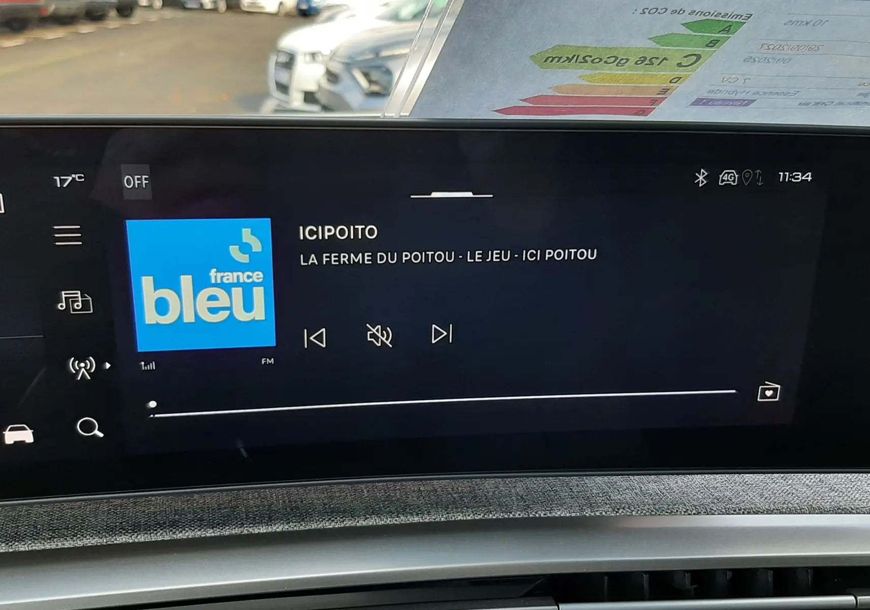 Vue intérieure du tableau de bord du Peugeot 5008 Bleu Ingaro, avec écran tactile affichant une radio FM.