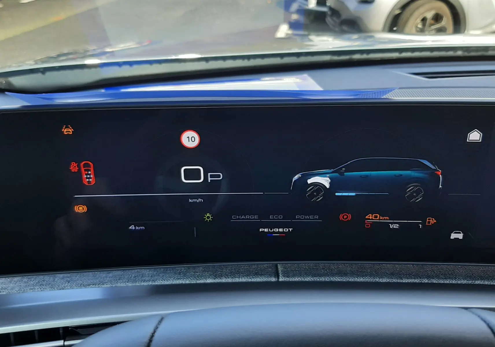 Tableau de bord numérique du Peugeot 5008 bleu Ingaro, affichant l'autonomie et l'état hybride en vue frontale depuis le siège conducteur.