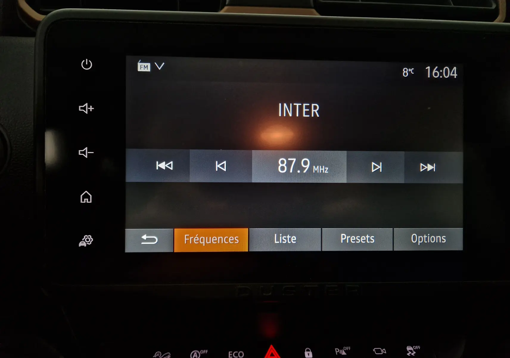 Écran tactile central du tableau de bord du Dacia Duster blanc 2024 affichant la radio FM sur 87.9 MHz à 16h04