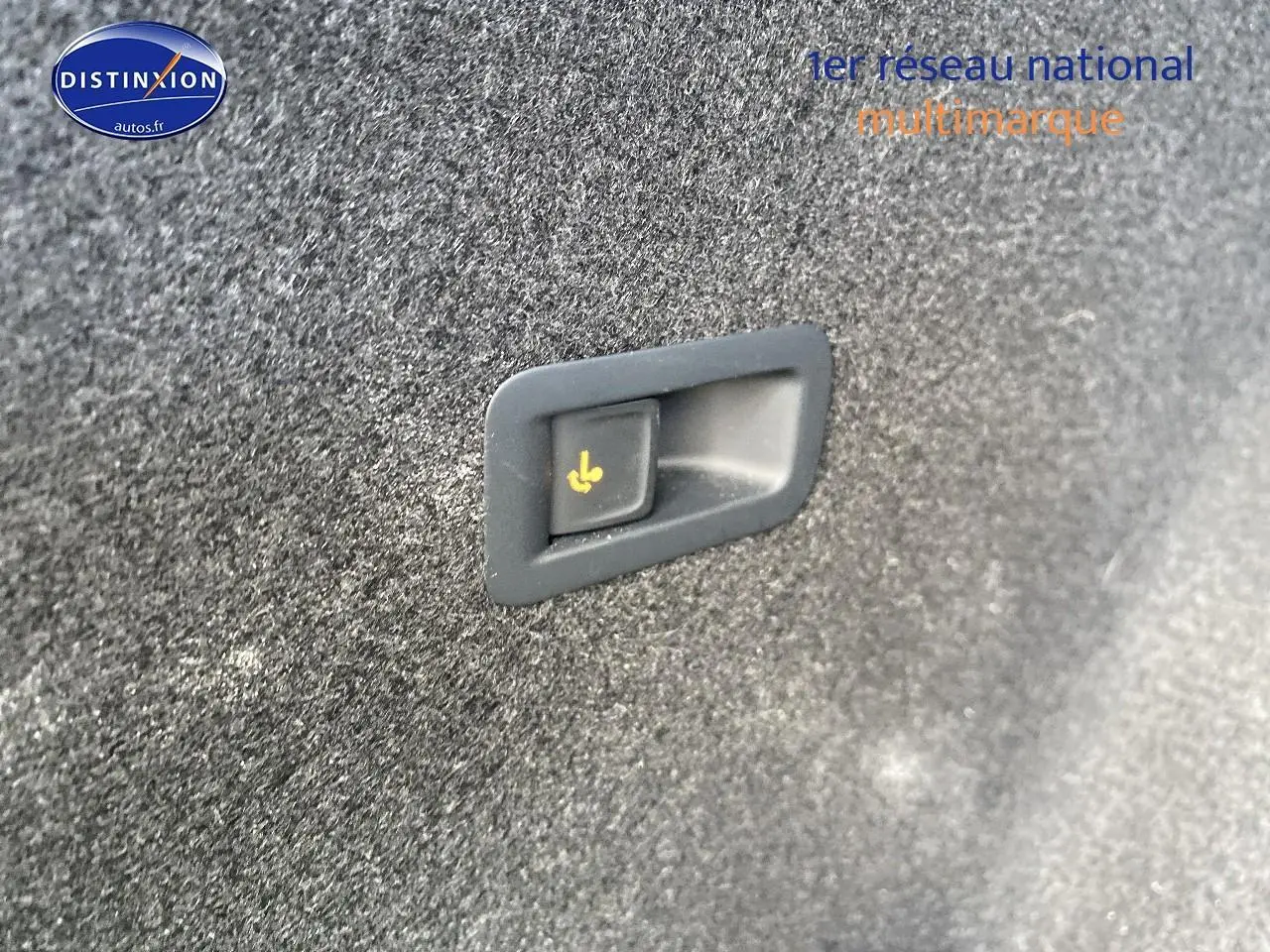 Bouton de rabattement électrique des sièges arrière sur revêtement intérieur gris foncé du coffre d'un CUPRA Formentor blanc.
