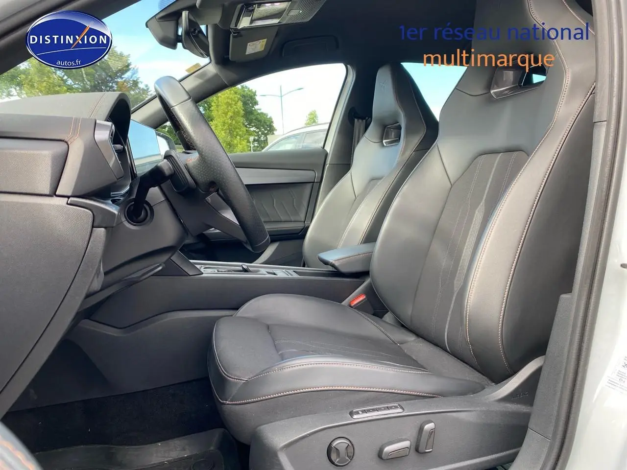 Vue intérieure côté conducteur du CUPRA Formentor blanc 2023, sièges sport en tissu noir avec surpiqûres cuivrées.