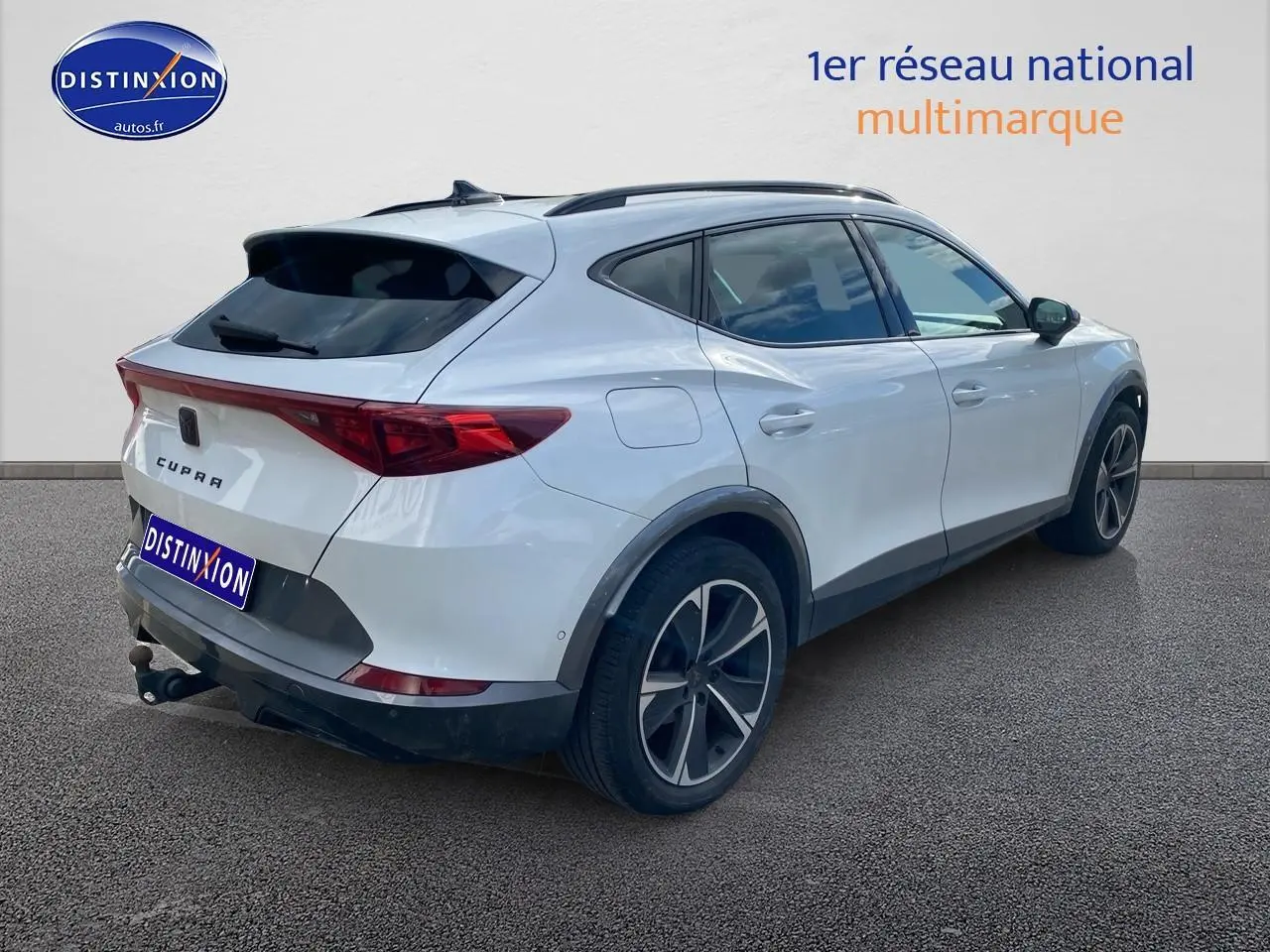 Vue 3/4 arrière droite d'un CUPRA Formentor blanc 2023 avec jantes alu noires et attelage visible.