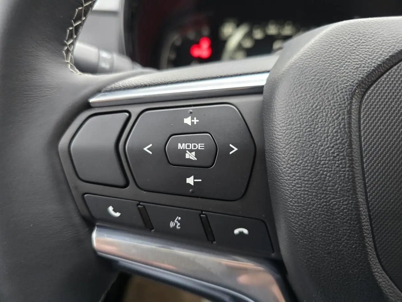 Gros plan sur les commandes audio et téléphone au volant en cuir noir de l'Isuzu D-MAX III NEW 2025.