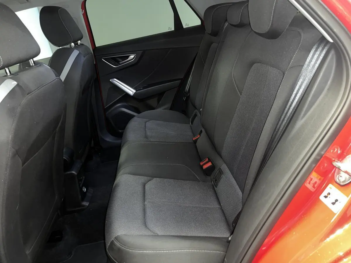 Vue intérieure côté droit des sièges arrière noirs de l'Audi Q2 rouge 2024 finition S line.