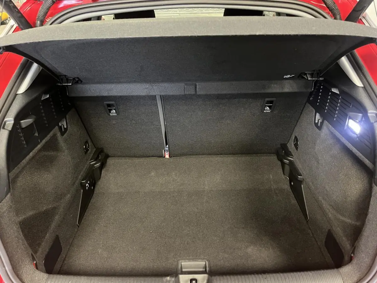 Vue intérieure du coffre ouvert de l'Audi Q2 rouge 2024, montrant un espace de rangement propre et spacieux.