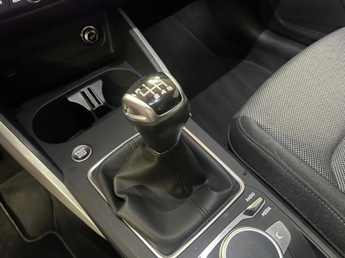 Le levier de vitesses manuel de l'Audi Q2 2024 en gros plan avec console noire et siège tissu gris.