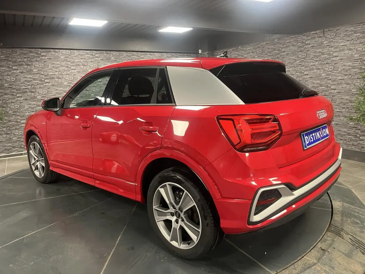 Audi Q2 rouge vue 3/4 arrière droit avec toit contrasté blanc et jantes sport 5 branches titanium mat.