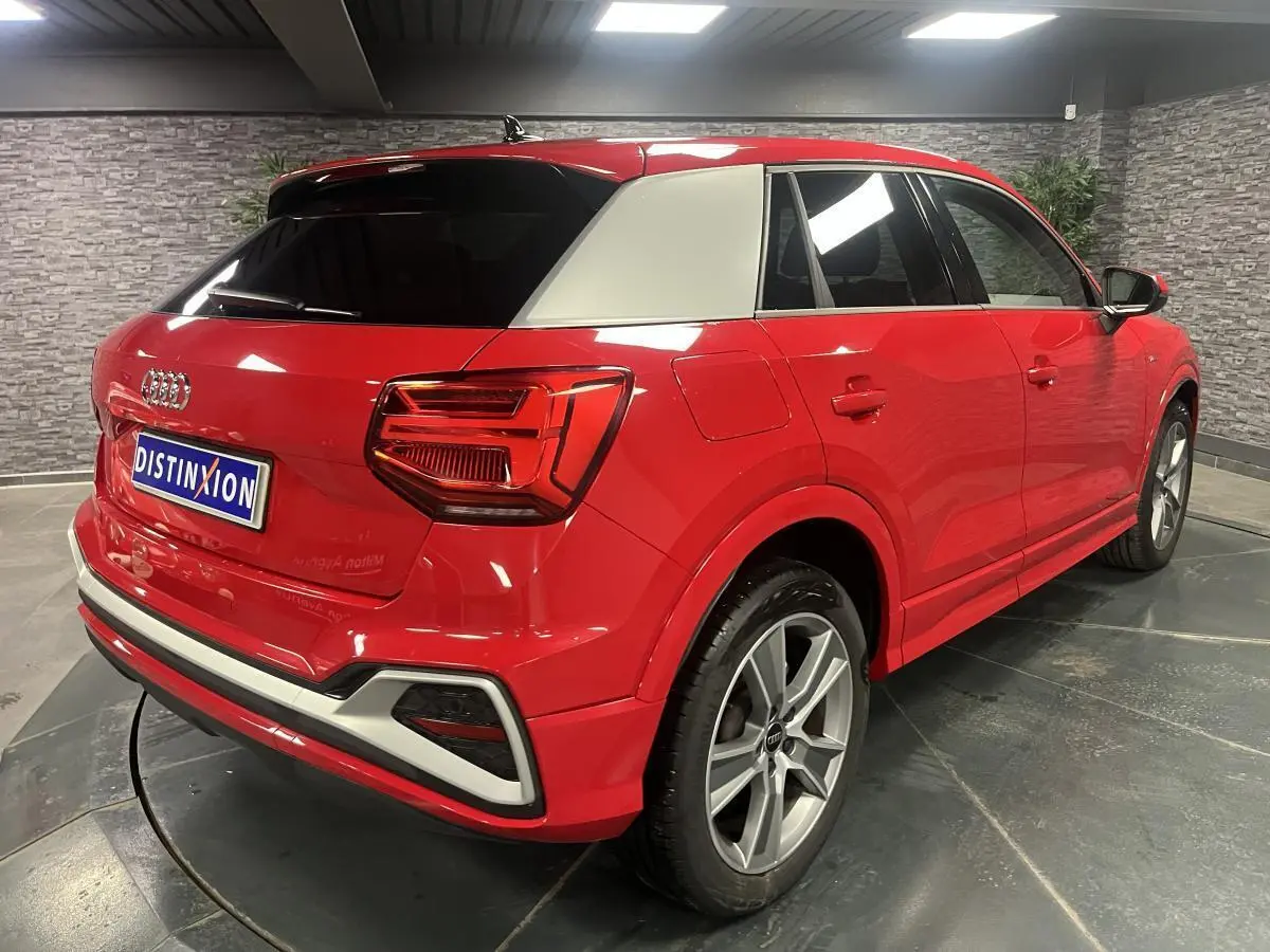 Audi Q2 rouge vue 3/4 arrière droit avec toit blanc contrasté et jantes sport 5 branches titanium mat.