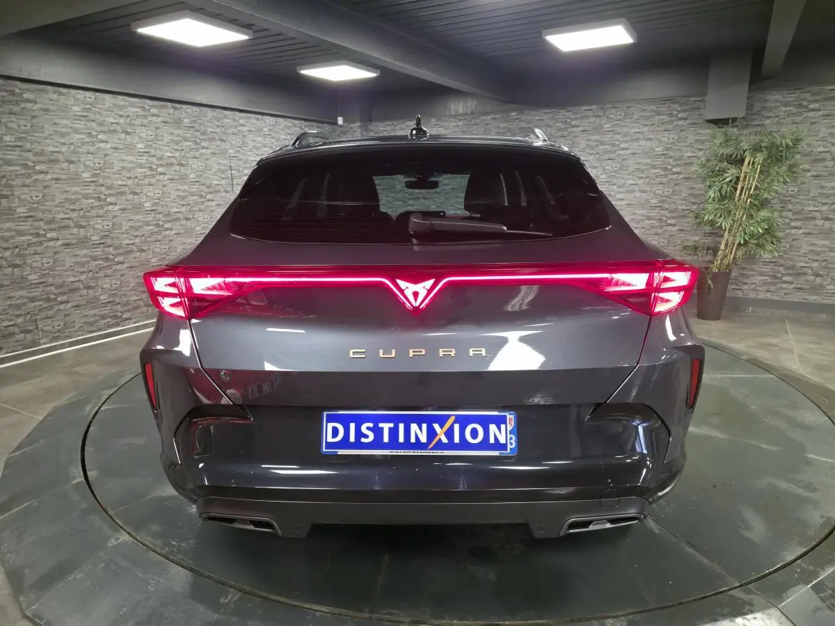Vue arrière d'une CUPRA Formentor gris métallisé avec signature lumineuse Tri-LED et double sortie d'échappement noire.