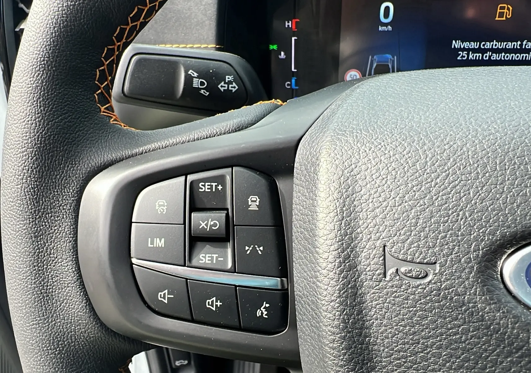Gros plan sur le volant cuir noir du Ford Ranger blanc glacier, avec commandes multifonctions et tableau de bord digital.
