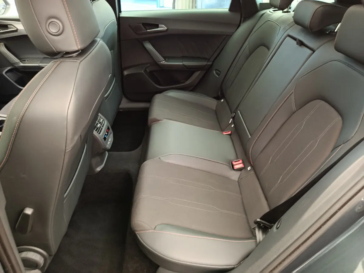 Vue intérieure côté droit des sièges arrière en cuir noir avec surpiqûres orange d'une CUPRA LEON ST 2024 gris foncé.