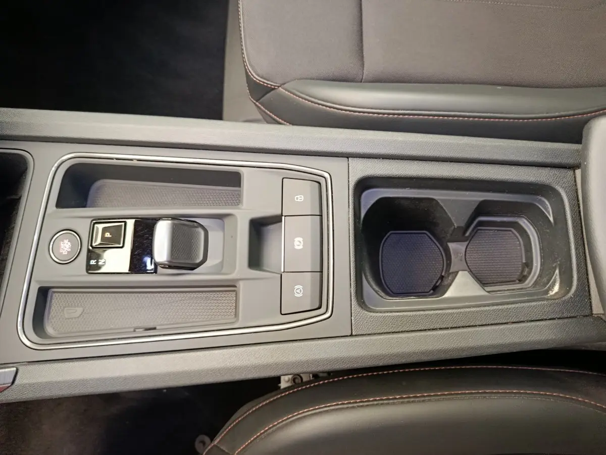 Vue plongeante sur la console centrale grise foncé de la CUPRA LEON ST 2024 avec levier de vitesse automatique et porte-gobelets.