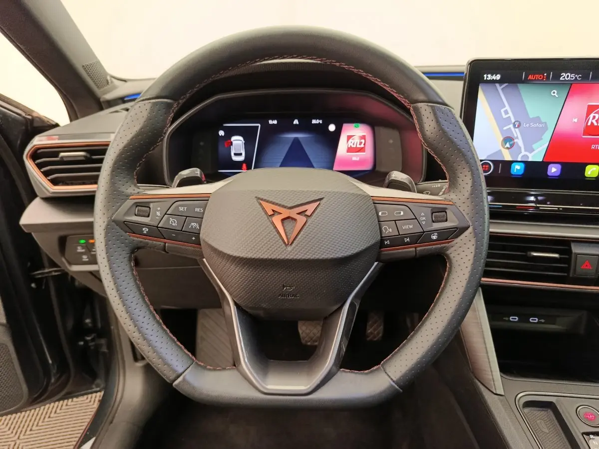 Vue intérieure centrée sur le volant cuir perforé avec logo CUPRA et écran tactile du tableau de bord du Leon ST 2024.