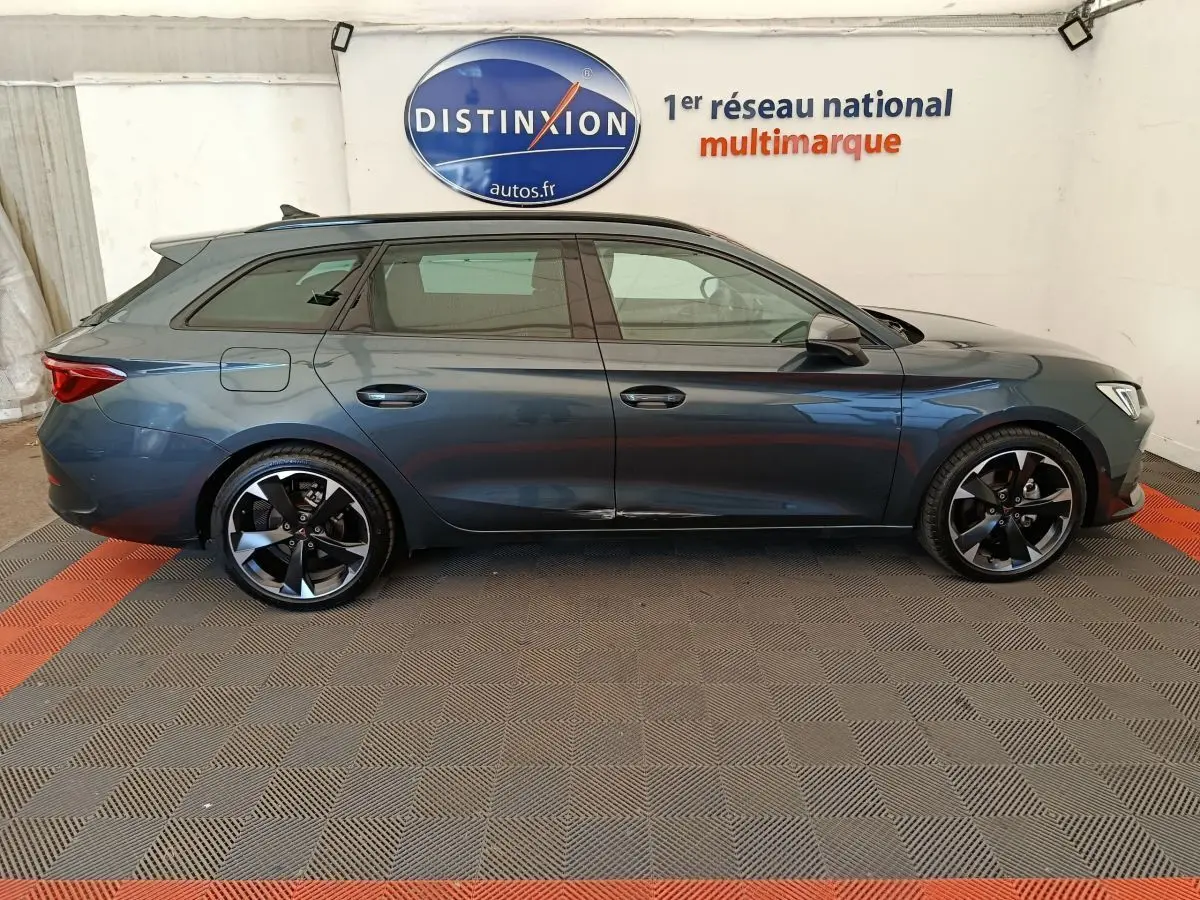 Profil droit d'une CUPRA LEON ST 1.5 eTSI 150 DSG7 gris foncé, avec jantes alliage noires et toit ouvrant visible.