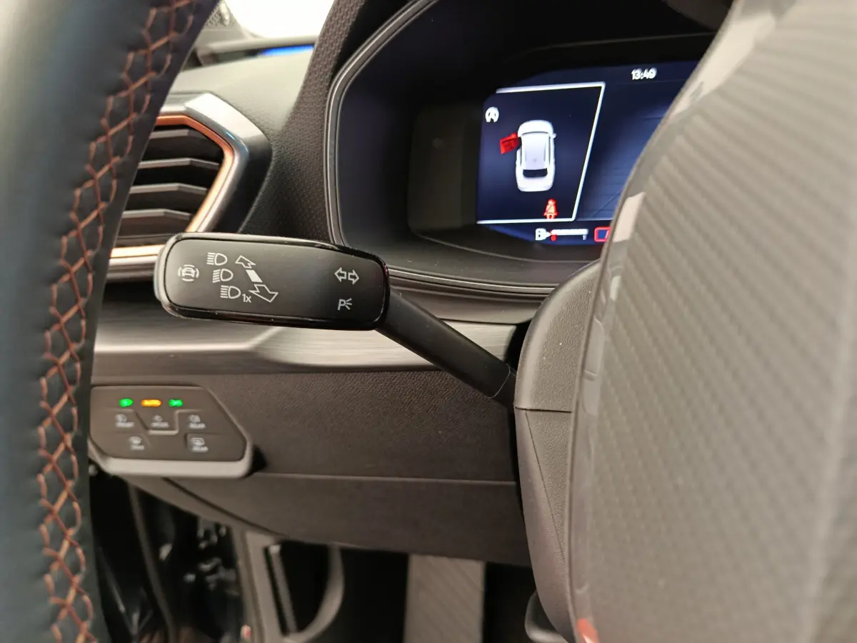 Gros plan sur la manette de clignotant à gauche du volant dans l'habitacle sombre de la CUPRA Leon ST 2024.