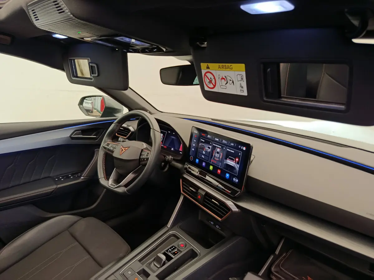 Intérieur côté conducteur de la CUPRA LEON ST 2024, tableau de bord moderne avec écran tactile et volant cuir noir.