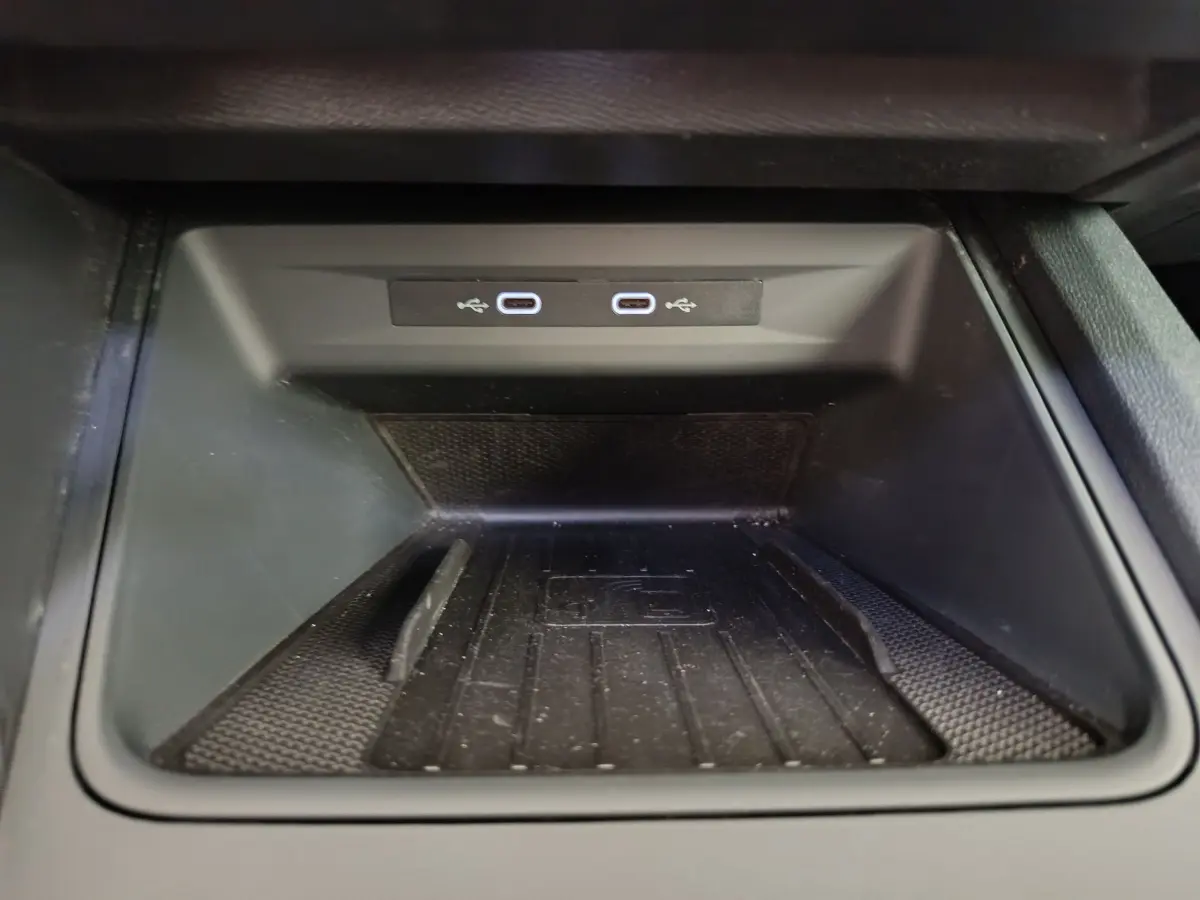 Gros plan sur la zone de recharge par induction avec deux ports USB-C dans la console centrale d'une CUPRA LEON ST gris foncé.