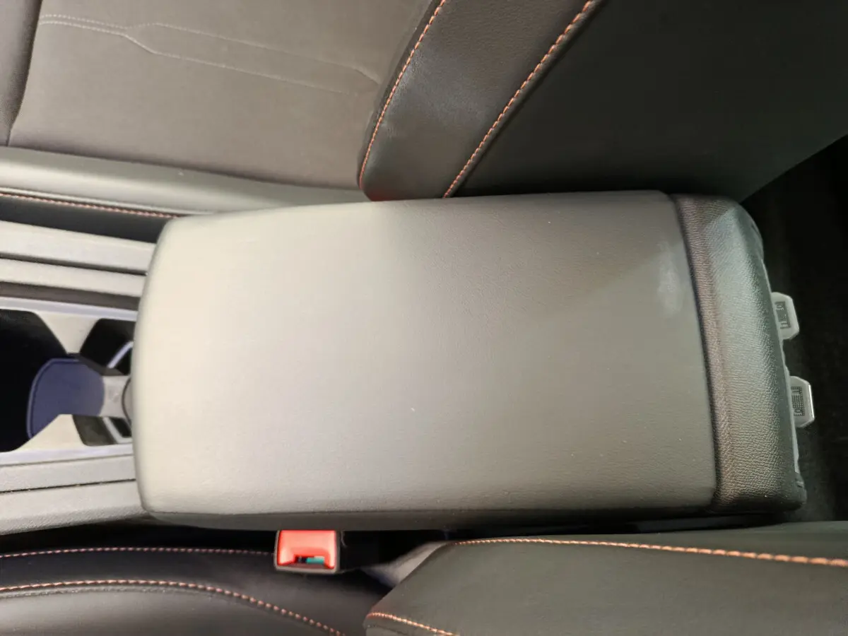 Accoudoir central noir avec surpiqûres orange dans l'habitacle du CUPRA LEON ST gris foncé 2024.