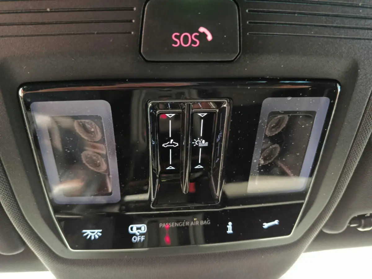 Vue rapprochée du panneau de commande intérieur noir avec bouton SOS et commandes d'éclairage de la CUPRA LEON ST 2024.