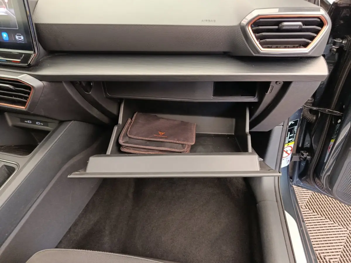 Vue intérieure du coffre à gants ouvert avec pochette noire dans une CUPRA LEON ST 2024 gris foncé.