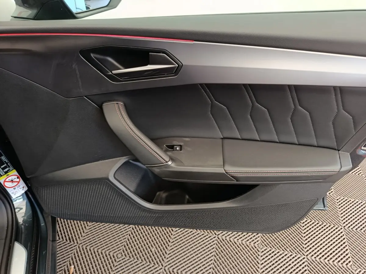 Panneau de porte côté gauche en cuir noir avec surpiqûres rouges du CUPRA LEON ST 2024 gris foncé.