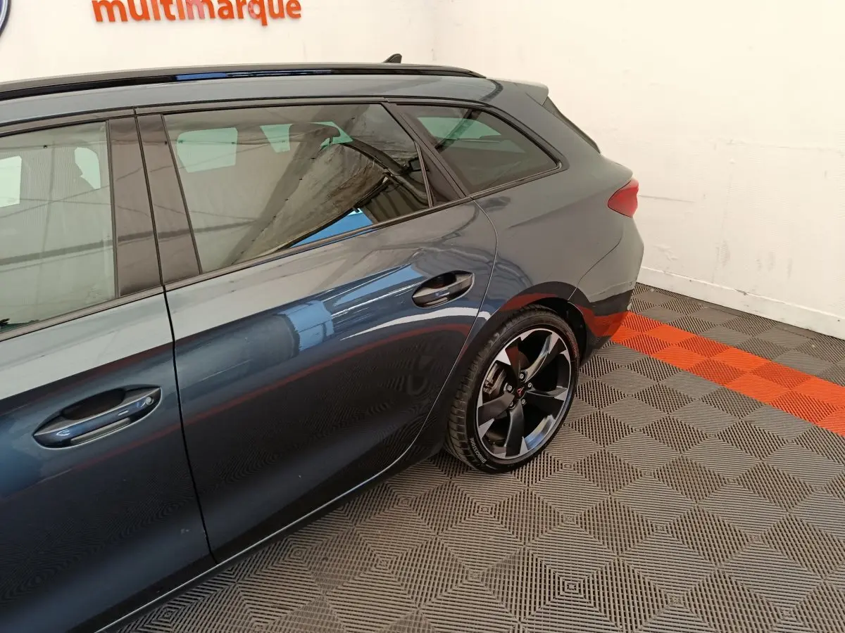 Vue latérale arrière droite d'une CUPRA LEON ST gris foncé avec jantes noires et poignées de porte intégrées.