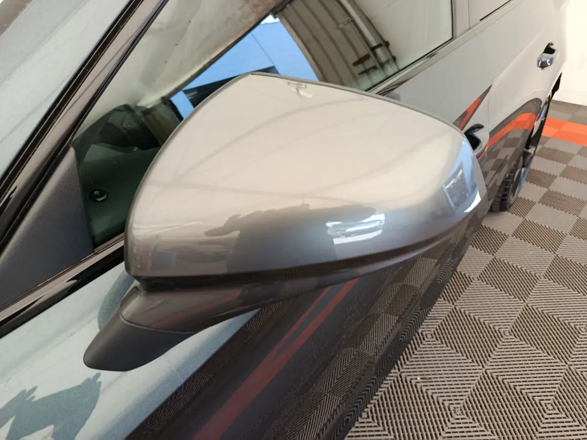 Rétroviseur droit gris foncé de la CUPRA LEON ST 2024, avec carrosserie et jante partiellement visibles en arrière-plan.