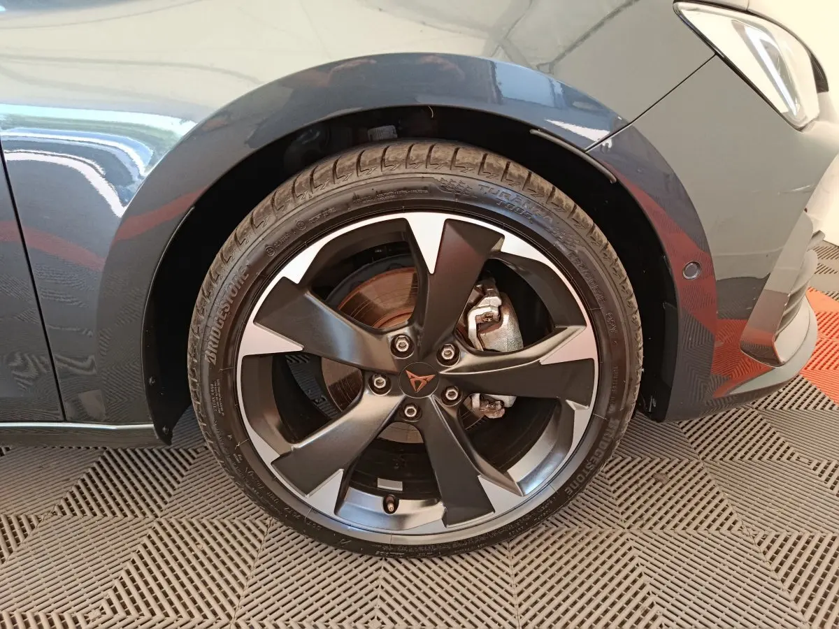 Gros plan sur la roue avant droite d'une CUPRA LEON ST gris foncé, avec jante alliage noire et grise distinctive.