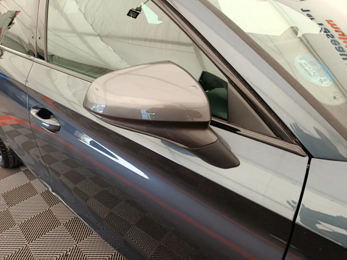Vue rapprochée du rétroviseur côté gauche d'une CUPRA LEON ST gris foncé avec portière et vitre avant visibles.