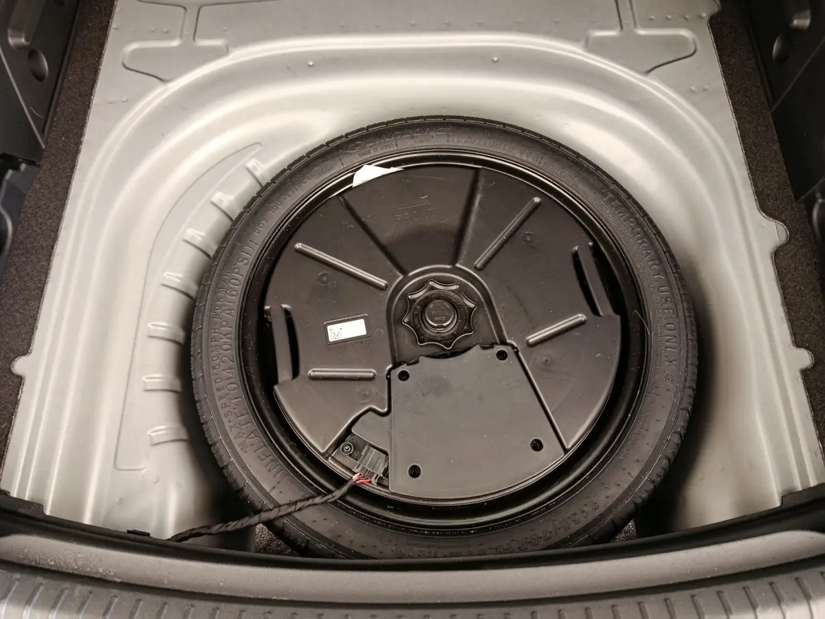 Vue plongeante sur la roue galette de secours dans le coffre gris foncé d'une CUPRA LEON ST 2024