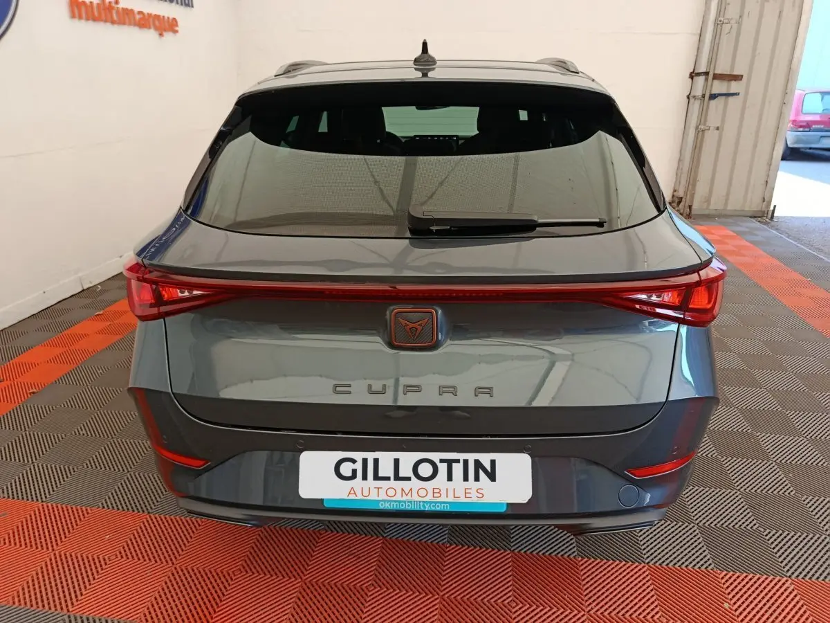 Vue arrière d'une CUPRA LEON ST gris foncé avec feux arrière LED reliés et logo CUPRA central lumineux.