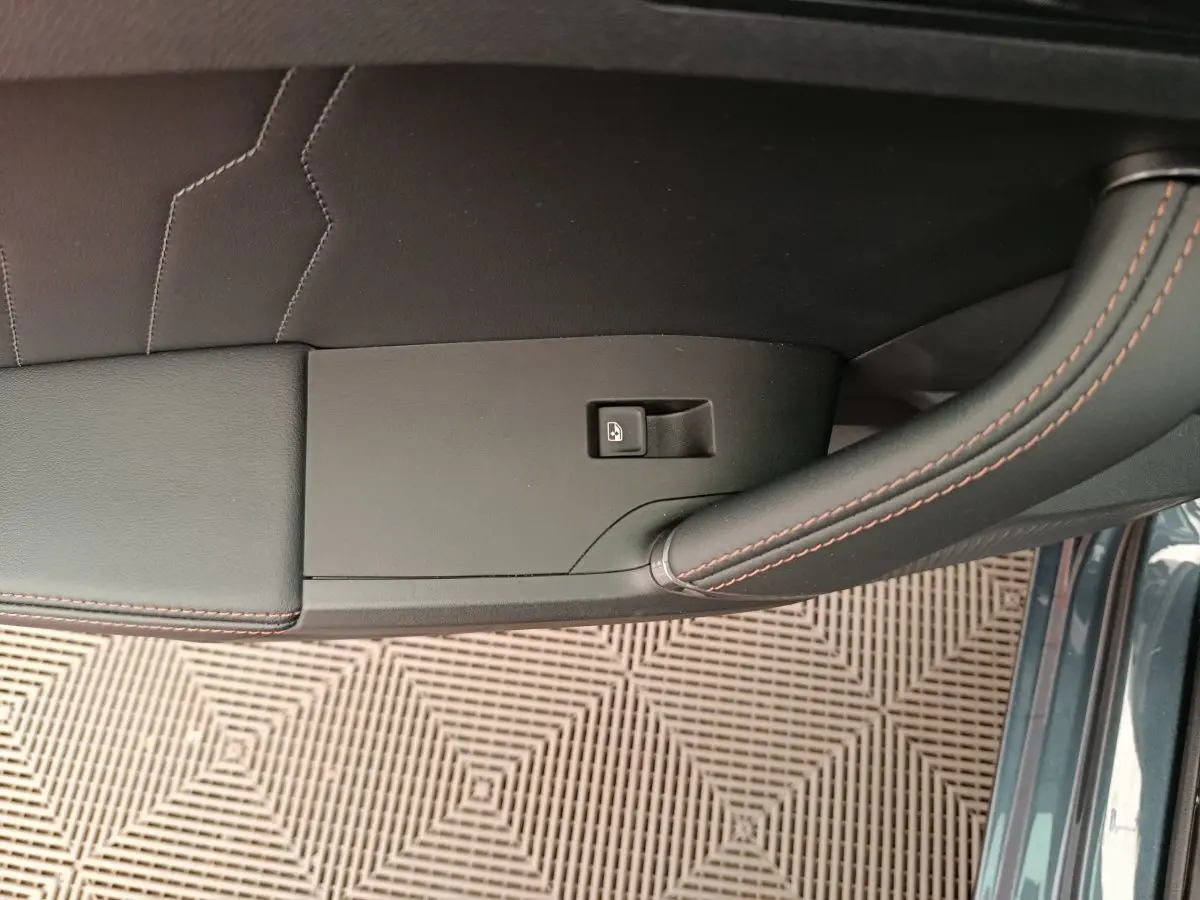 Gros plan sur la poignée intérieure côté gauche de la porte d'une CUPRA LEON ST gris foncé avec surpiqûres orange.