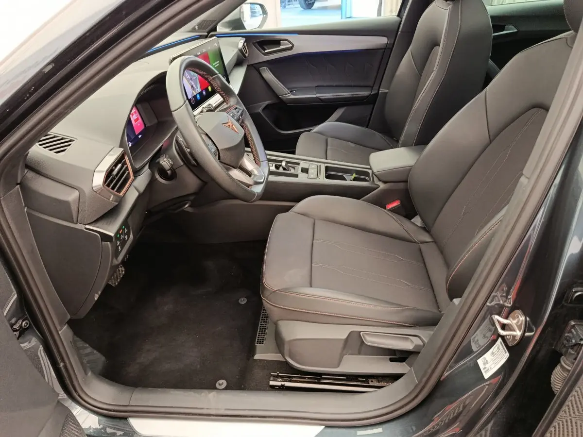 Intérieur côté conducteur de la CUPRA LEON ST gris foncé 2024, avec tableau de bord digital et sièges noirs élégants.