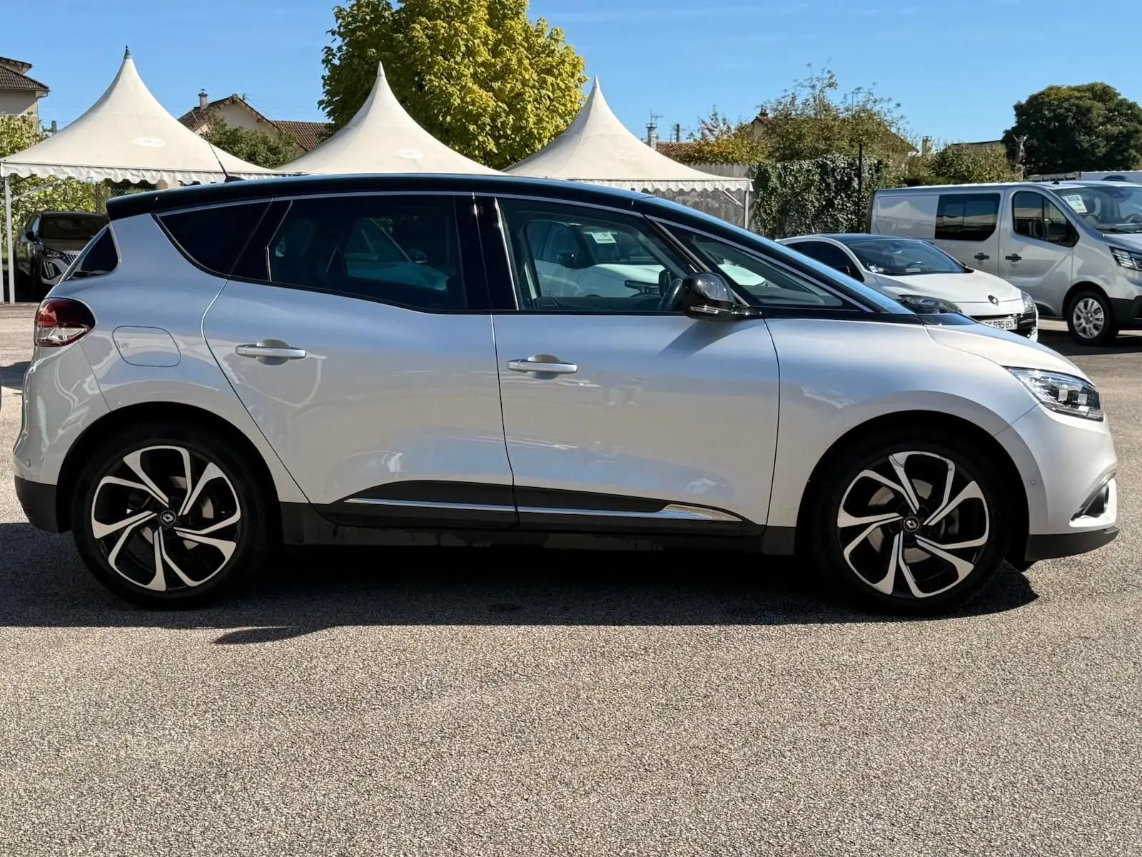 Profil côté gauche d'un Renault Scénic IV gris platine avec toit noir étoile, roues alliage au design moderne, en extérieur.