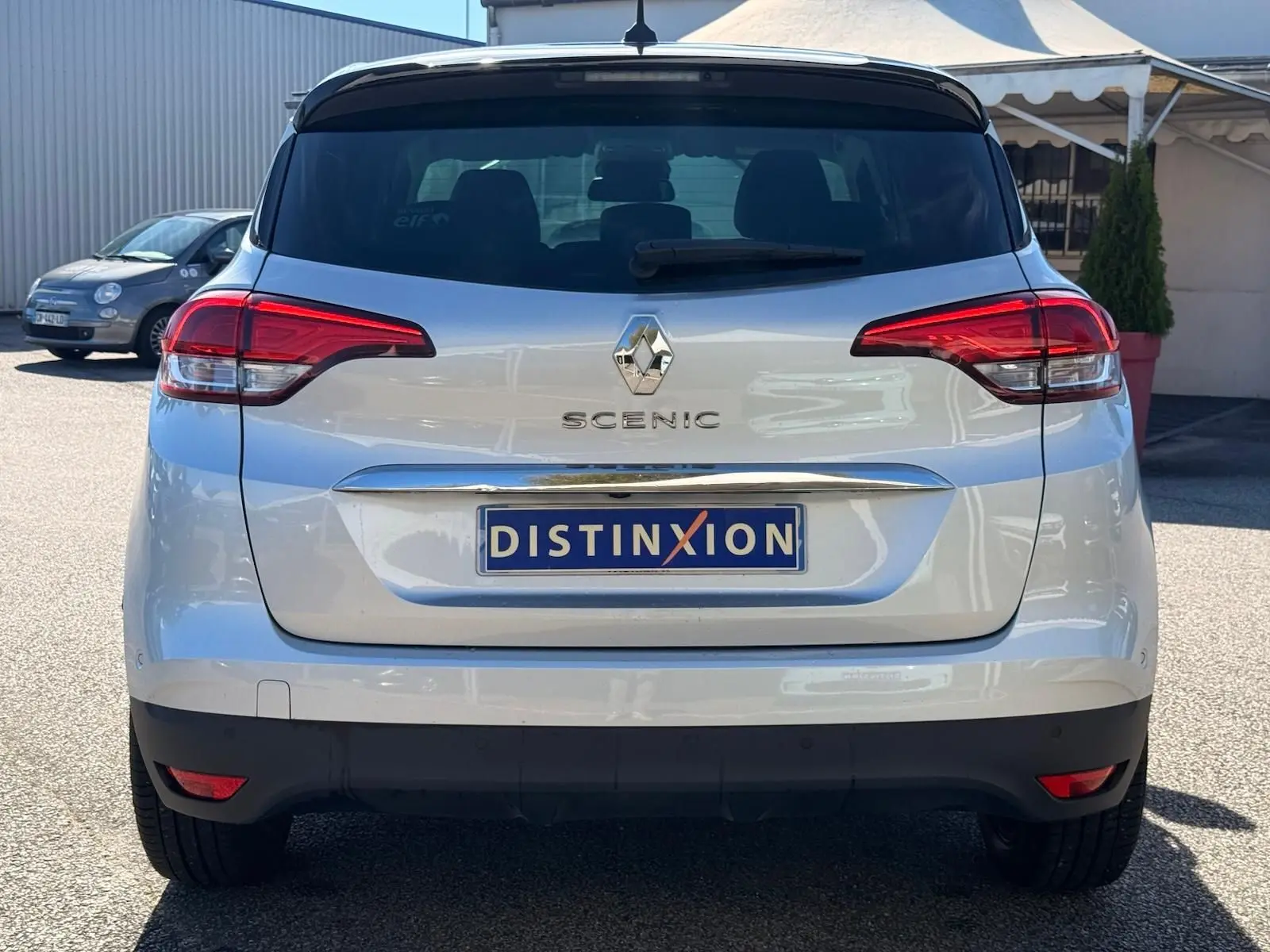 Vue arrière d'un Renault Scénic IV gris platine avec toit noir, mettant en valeur les feux arrière et le logo central.