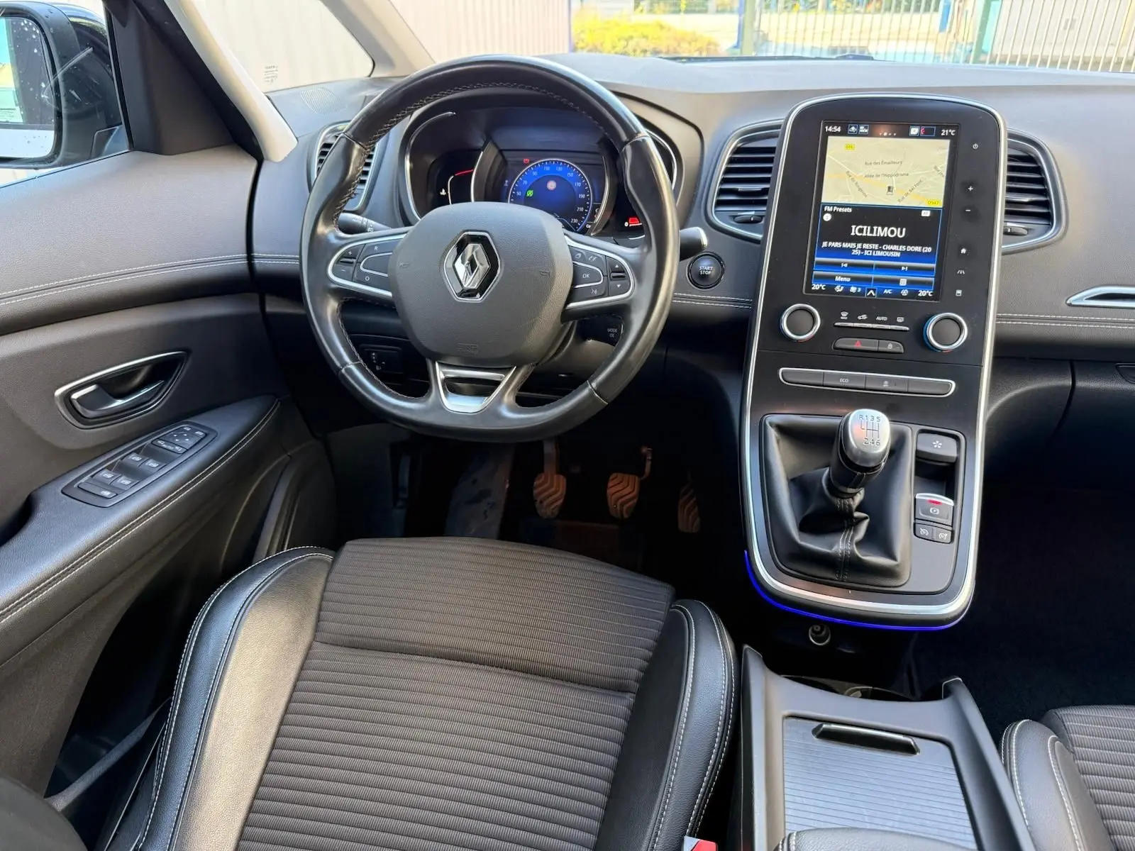 Vue intérieure avant du Renault Scenic IV 1.7 Blue dCi avec volant, tableau de bord numérique et levier de vitesse manuel.