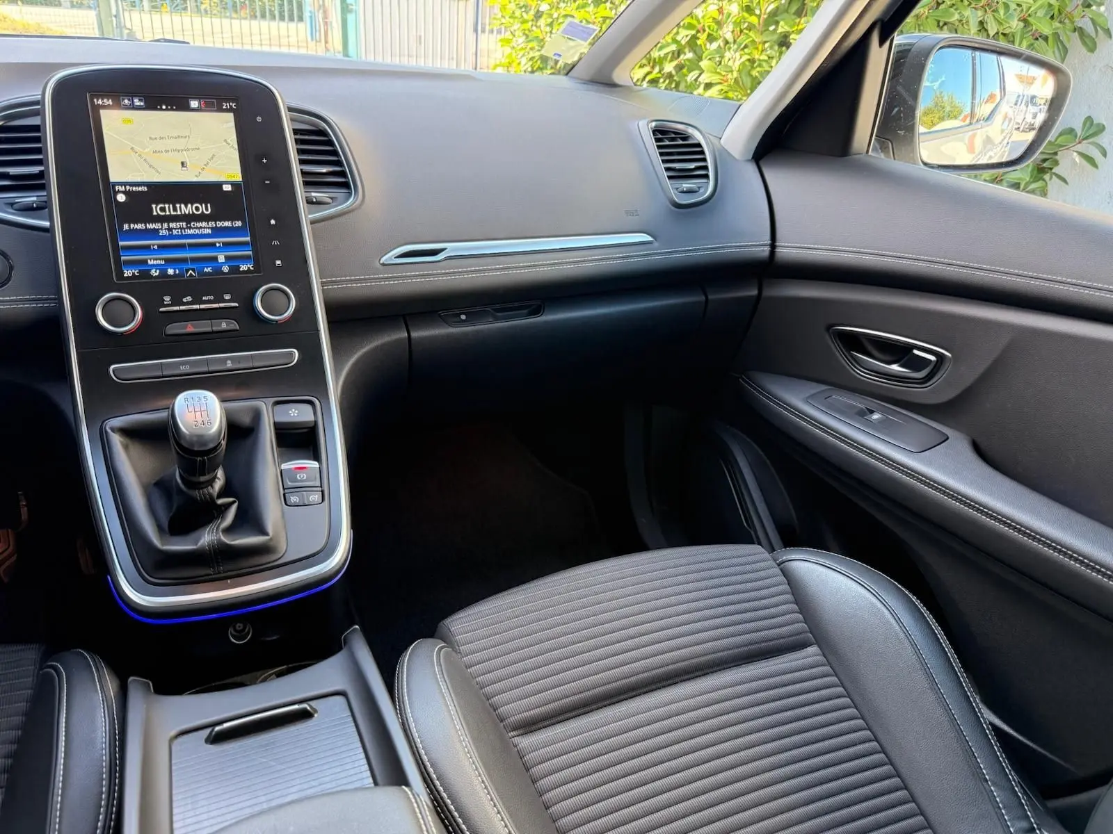 Intérieur avant droit du Renault Scenic IV gris platine, avec console centrale et levier de vitesse manuelle visible.