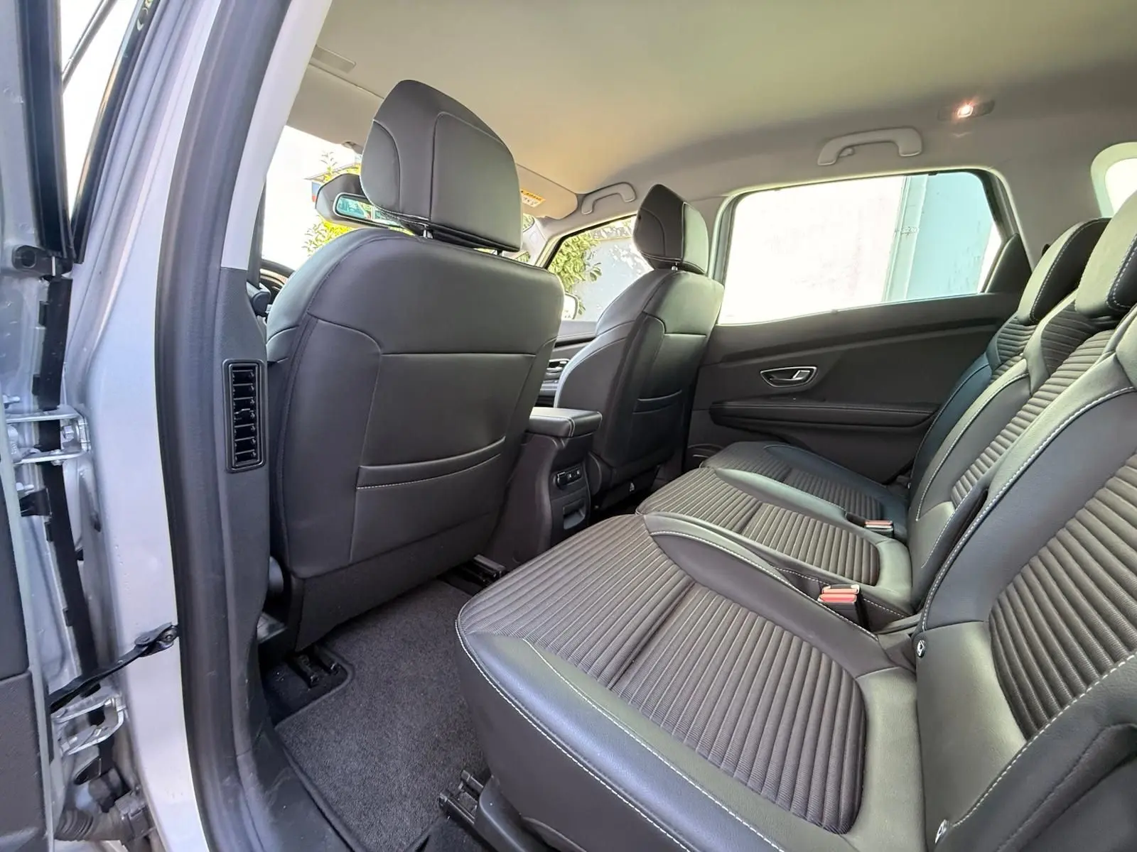 Vue intérieure arrière du Renault Scenic IV 2020 gris platine, montrant les sièges noirs et l'espace aux jambes côté droit.