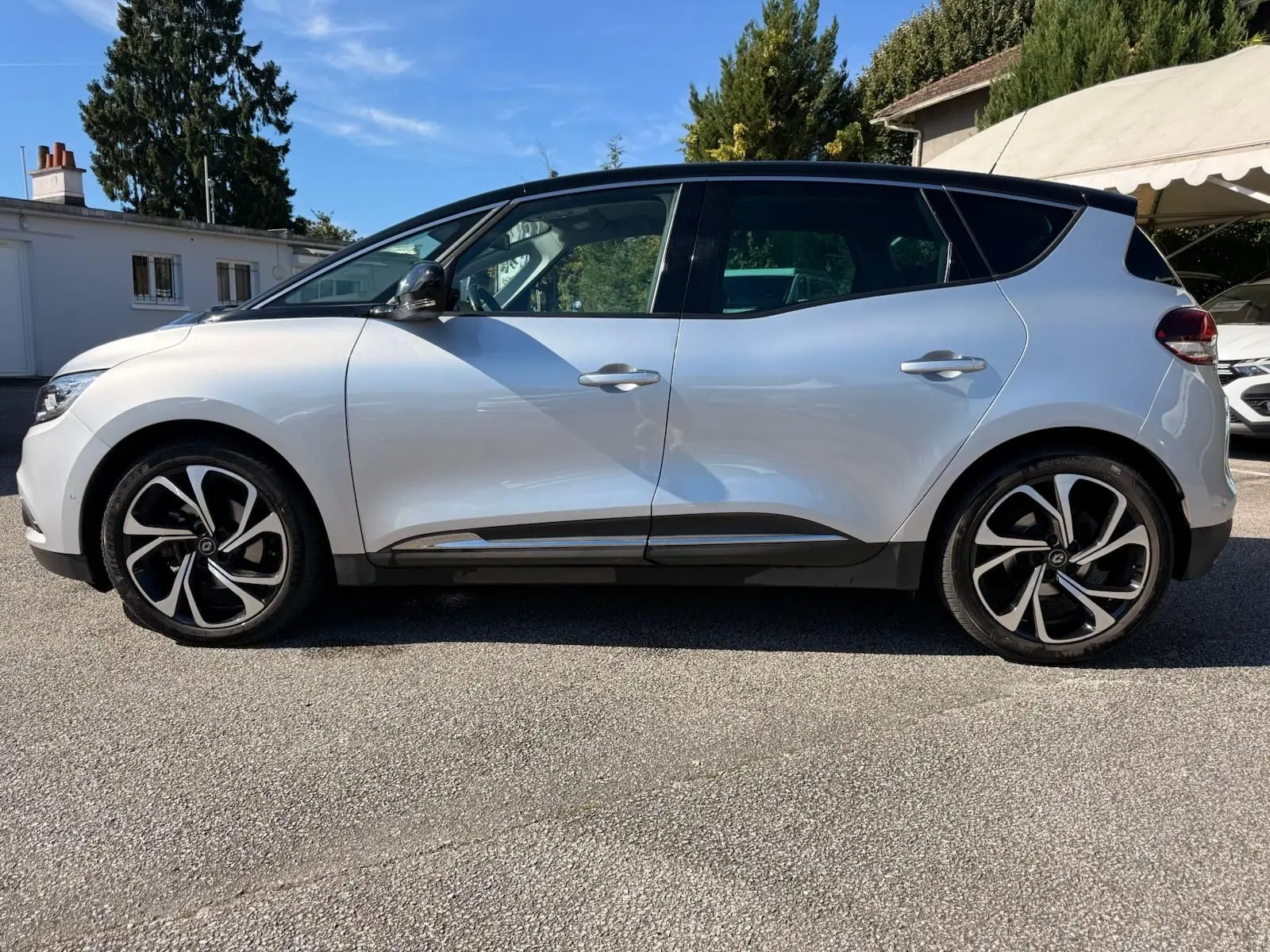 Profil côté gauche d'un Renault Scénic IV gris platine avec toit noir étoile et jantes alliage distinctives.