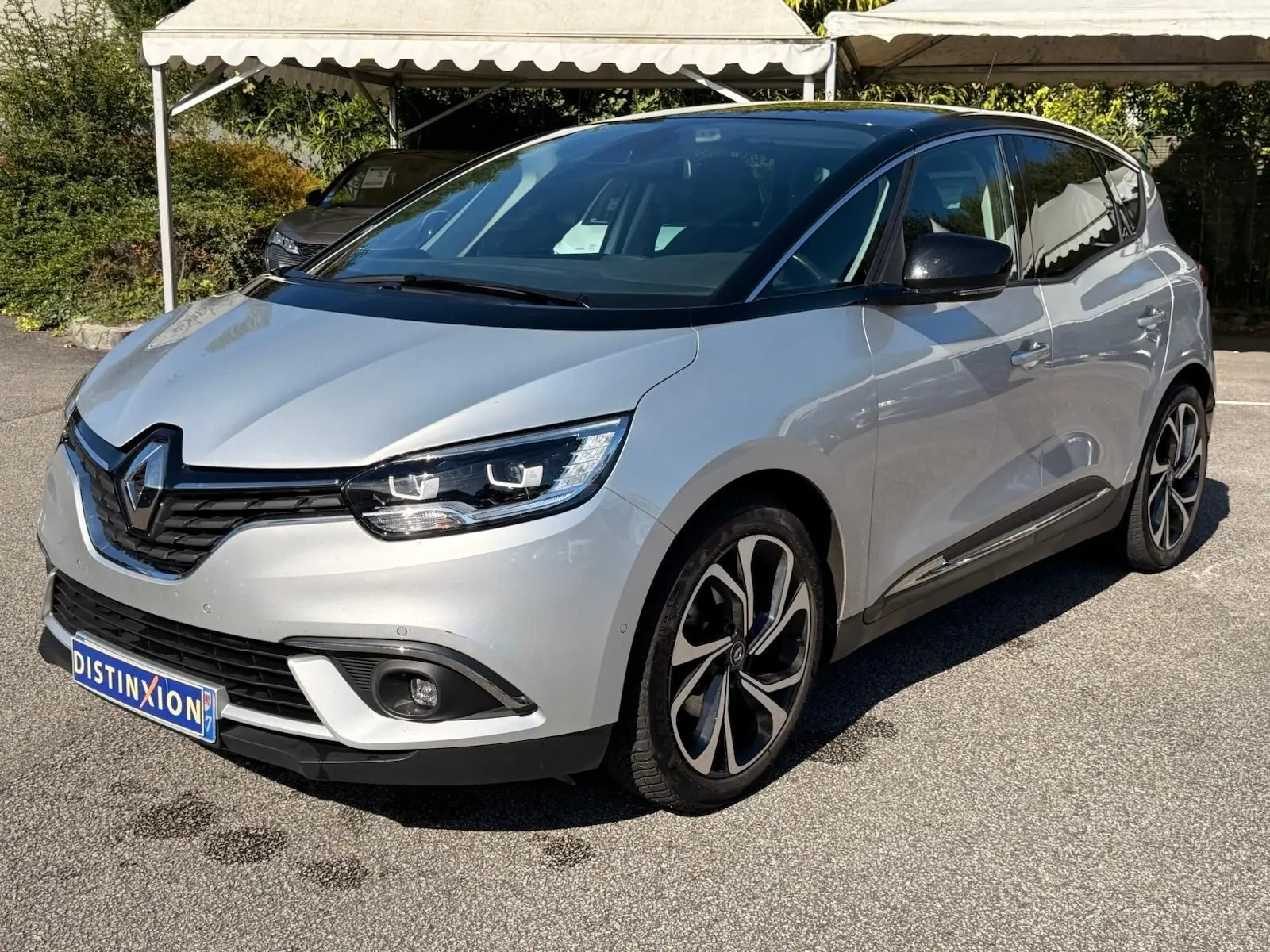 Renault Scénic IV gris platine avec toit noir, vue 3/4 avant droit mettant en valeur ses optiques LED et jantes distinctives.