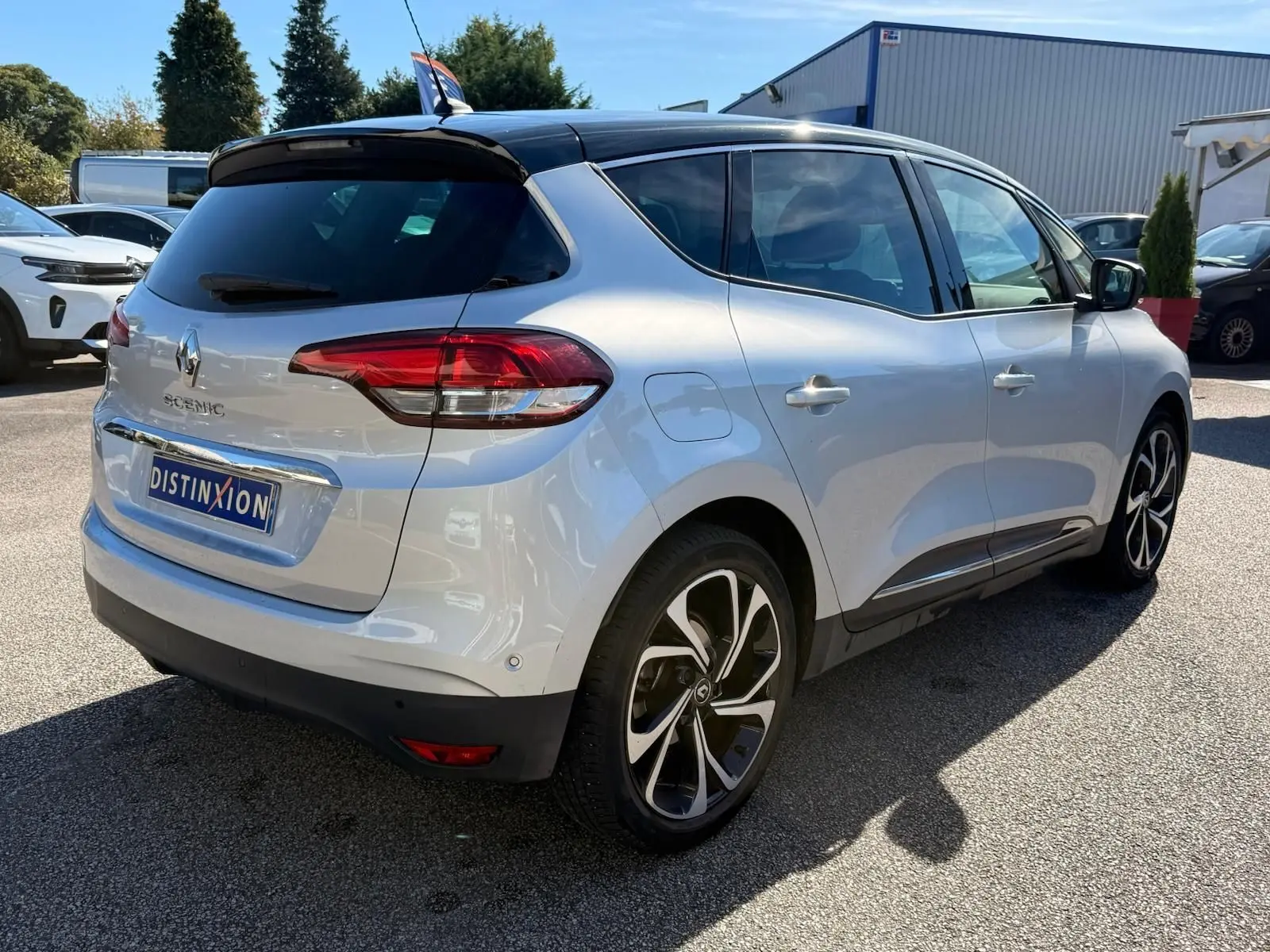 Vue 3/4 arrière droite d'un Renault Scénic IV gris platine avec toit noir étoile et jantes distinctives.