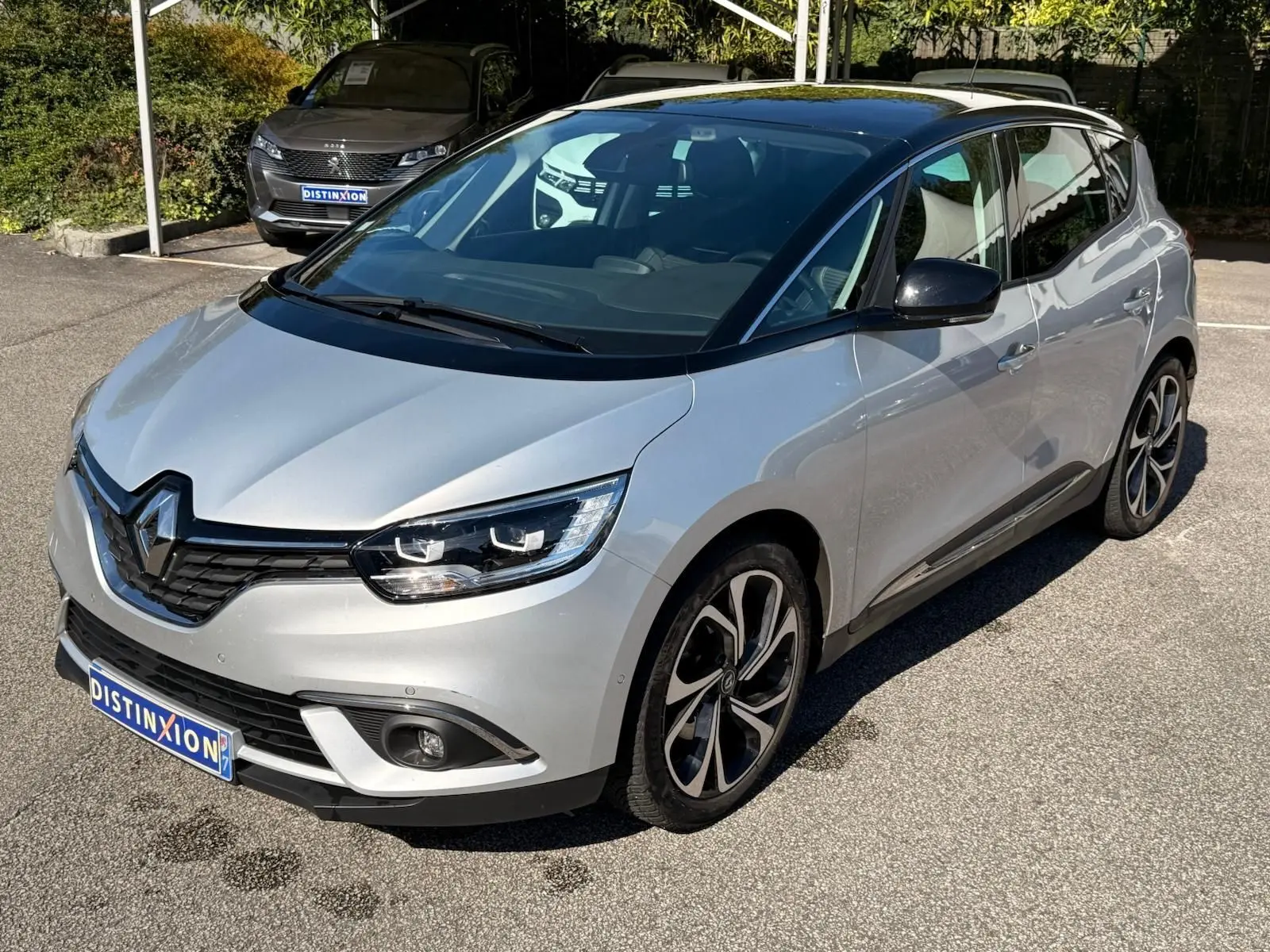 Renault Scénic IV gris platine avec toit noir, vue 3/4 avant droit mettant en valeur ses jantes distinctives.