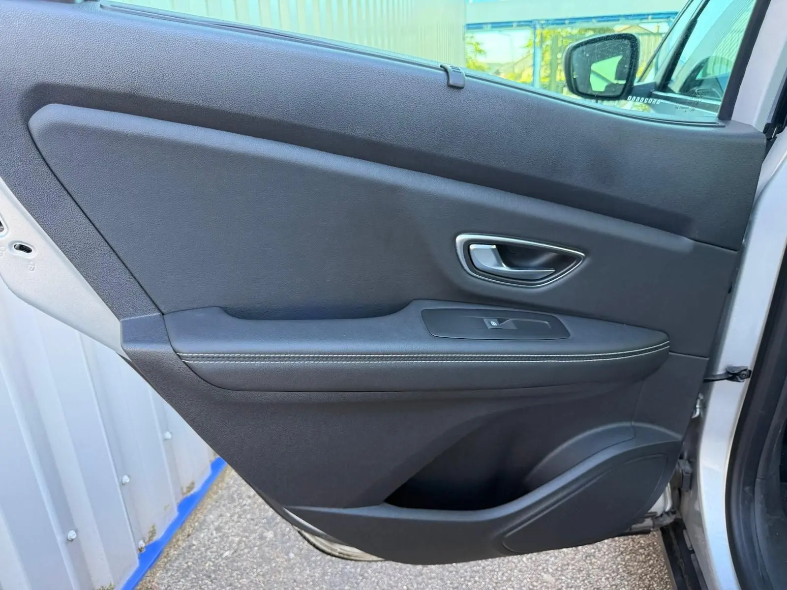 Porte intérieure côté gauche de Renault Scenic IV 2020 gris platine, avec poignée argentée et bouton de vitre électrique.